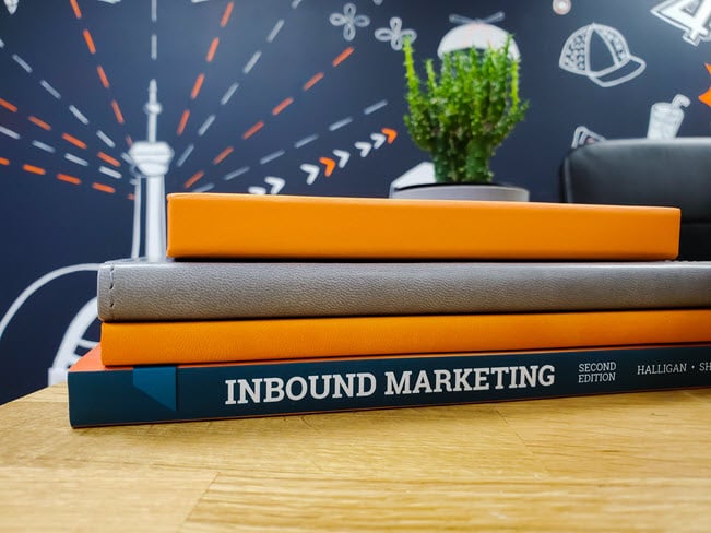 Stack of Inbound Marketing books in front of a Toronto mural